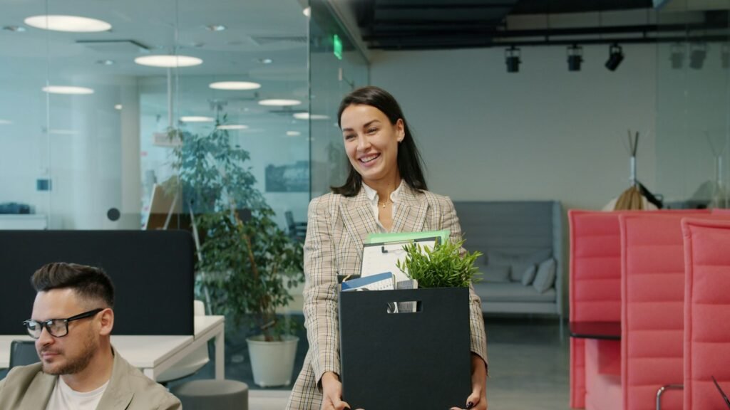 Trabajadora saliendo de la oficina con una caja de sus pertenencias